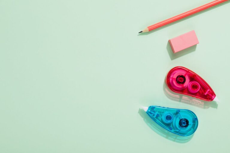 Arrangement of pencil, eraser, and correction tape on a pastel surface.