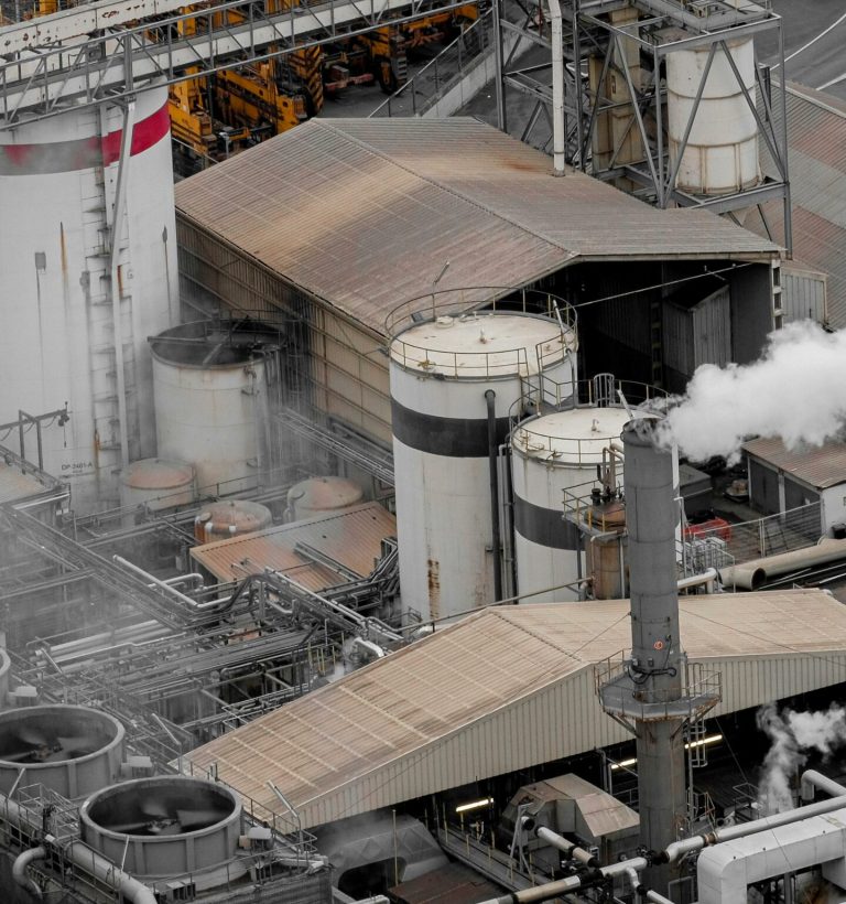 Bird's-eye view of intricate machinery and pipework at an industrial factory, showcasing production activity.